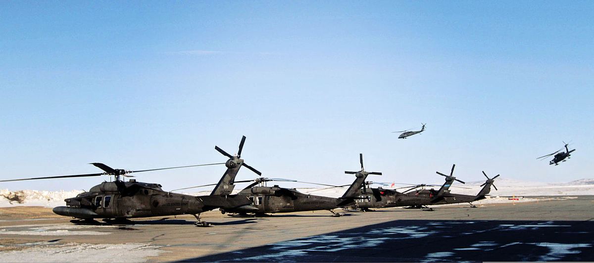 U.S. Army Black Hawk helicopters on an Alaska airfield with snowy hills under a clear sky