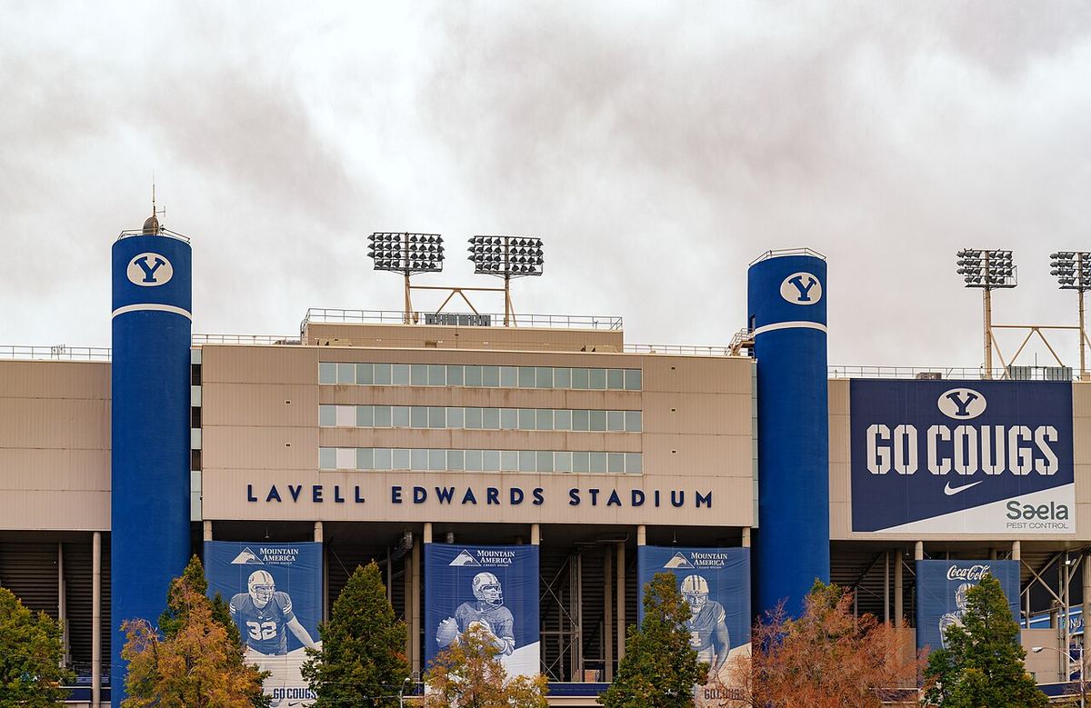 The front of LaVell Edwards Stadium in Provo, Utah, with blue BYU towers and a GO COUGS banner under a cloudy fall sky